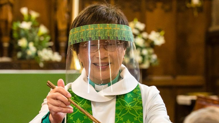 Rev Harrop enfile une visière ou un masque facial comme mesure de protection pendant ses services
