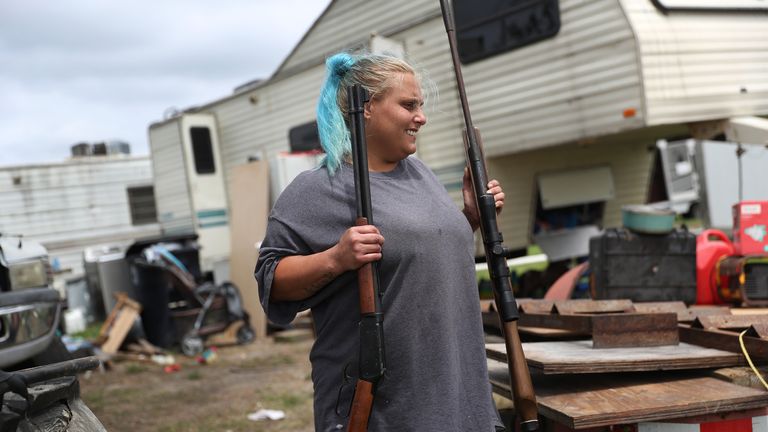 Une femme sort des fusils de sa maison alors qu'elle évacue avant l'arrivée possible de l'ouragan Laura, à Cameron, en Louisiane