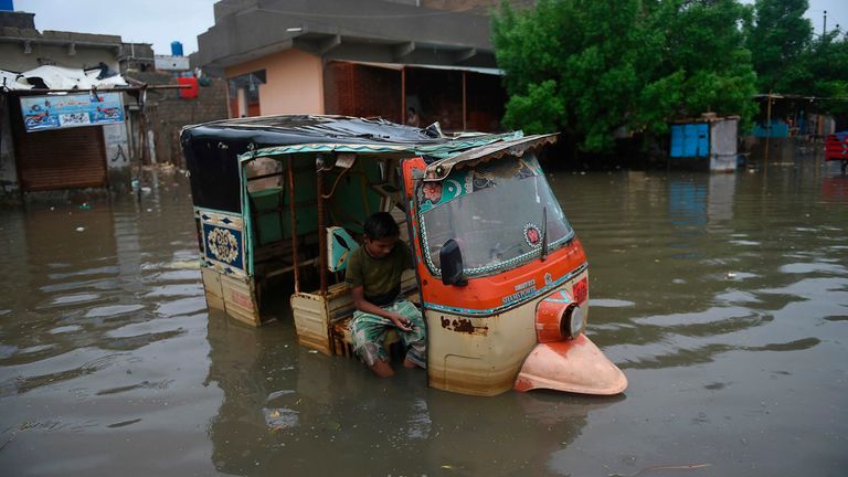 Un garçon est assis dans un auto-pousse-pousse dans une zone inondée après de fortes pluies de mousson dans la ville portuaire de Karachi au Pakistan 