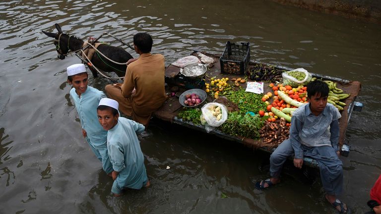 Un vendeur de légumes monte sur sa charrette à âne dans une rue inondée de Karachi 