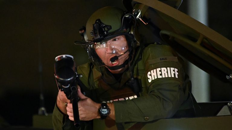 Un agent des forces de l'ordre tient une arme alors qu'il se tient dans l'écoutille d'un véhicule blindé alors que les gens manifestent devant le palais de justice du comté de Kenosha après qu'un homme noir, identifié comme Jacob Blake, ait été abattu à plusieurs reprises par la police à Kenosha, Wisconsin, États-Unis le 25 août 2020. REUTERS / Stephen Maturen