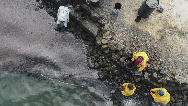 Une vue aérienne de personnes qui récupèrent du pétrole s'échappant des eaux au large de l'île Maurice