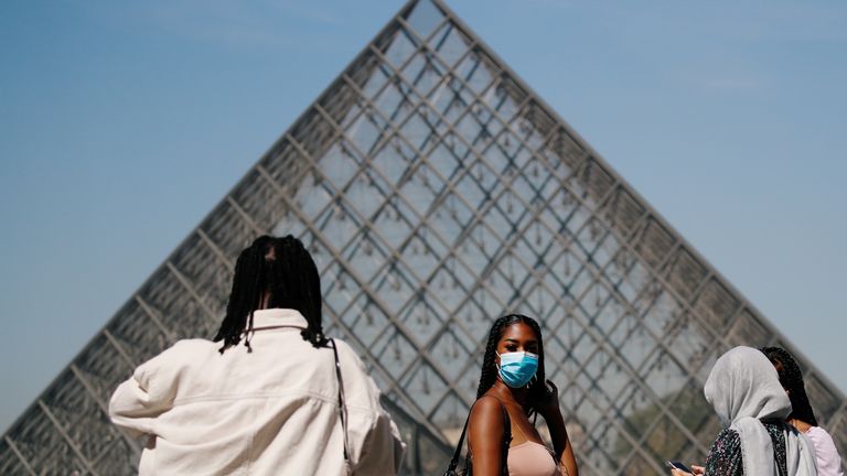 Une femme porte un masque facial à l'extérieur du Louvre dans la capitale française