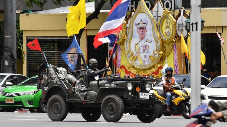 Un manifestant royaliste agite un drapeau national thaïlandais en passant devant un rassemblement à Bangkok le 16 août 2020, avant les manifestations anti-gouvernementales dans la capitale thaïlandaise.  - Une cinquantaine de manifestants royalistes se sont rassemblés le 16 août à Democracy Monument, le même lieu où les manifestants anti-gouvernementaux doivent se rassembler à Bangkok contre le gouvernement du Premier ministre Prayut-O-Cha alors que les tensions montent dans le royaume après l'arrestation de trois militants le mouvement pro-démocratie.  (Photo par Mladen ANTONOV / AFP) (Phot
