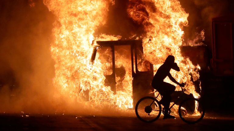 Un homme à vélo passe devant un camion de la ville en feu devant le palais de justice du comté de Kenosha à Kenosha, Wisconsin, États-Unis, lors de manifestations après la fusillade par la police de l'homme noir Jacob Blake le 23 août 2020.Photo prise le 23 août 2020. Mike De Sisti / Milwaukee Journal Sentinel via USA TODAY via REUTERS CRÉDIT OBLIGATOIRE
