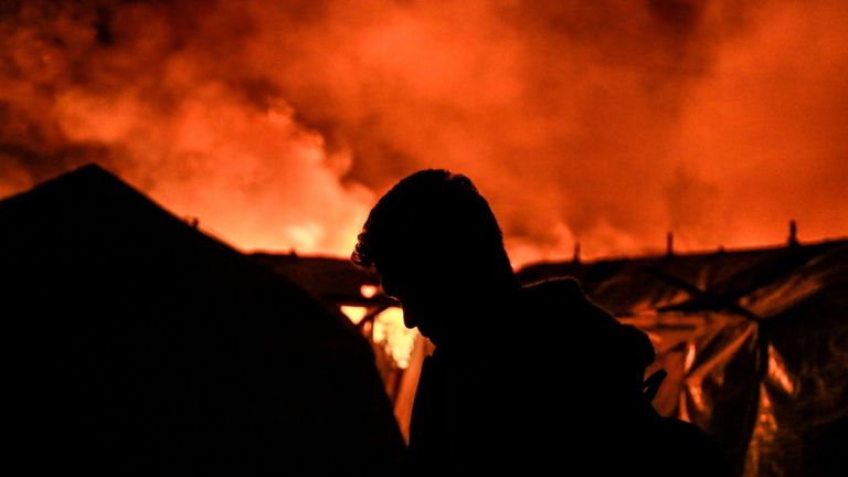 Des migrants partent alors qu'un feu brûle dans le camp de Moria sur l'île de Lesbos le 9 septembre 2020