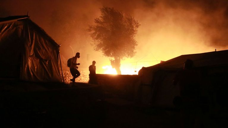 Des migrants partent alors qu'un feu brûle dans le camp de Moria sur l'île de Lesbos le 9 septembre 2020