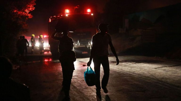 Des migrants partent alors qu'un feu brûle dans le camp de Moria sur l'île de Lesbos le 9 septembre 2020