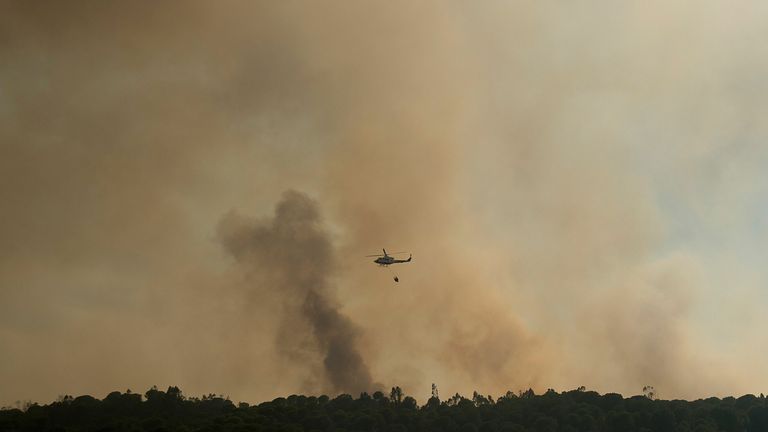 Un hélicoptère laisse tomber de l'eau sur un feu de forêt qui fait rage près d'El Buitron à Huelva, Espagne