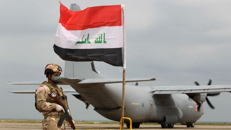 Un soldat irakien monte la garde devant le transporteur aérien militaire américain à la base aérienne de Qayyarah