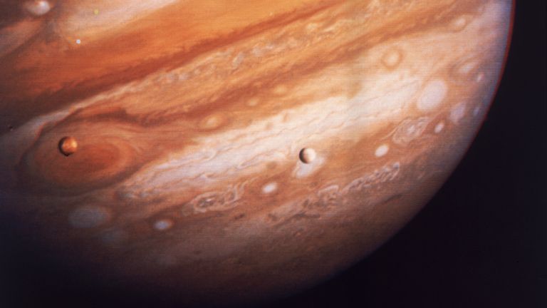 Jupiter, la plus grande planète de notre système solaire, avec deux de ses satellites, Io à gauche et Europa à droite