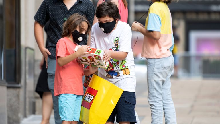 Des enfants portant des masques regardent une boîte Lego à l'extérieur du magasin Lego du Rockefeller Center alors que la ville poursuit la phase 4 de la réouverture à la suite des restrictions imposées pour ralentir la propagation du coronavirus le 2 août 2020 à New York. 