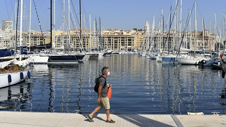 Un homme portant un masque facial marche sur une jetée du Vieux-Port de Marseille