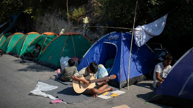 Un garçon joue de la guitare dans la zone où sont abrités les réfugiés et les migrants du camp détruit de Moria, près d'un nouveau camp temporaire, sur l'île de Lesbos, Grèce, le 16 septembre 2020. REUTERS / Alkis Konstantinidis