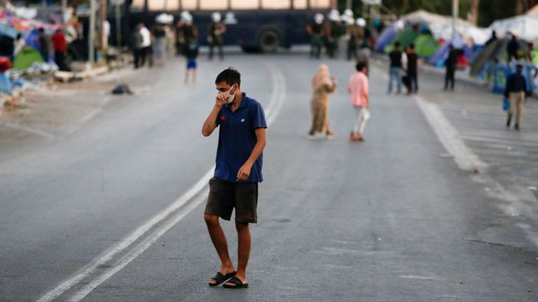 Un homme portant un masque protecteur fait son chemin le long d'une route bloquée par la police dans une zone où les réfugiés et les migrants du camp détruit de Moria sont abrités, lors d'une opération visant à les déplacer vers un nouveau camp temporaire, sur l'île de Lesbos, Grèce , 17 septembre 2020. REUTERS / Elias Marcou REFILE - CORRECTION DE LA DESCRIPTION DE L'OPERATION