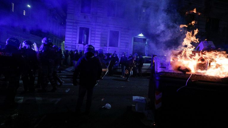 Des policiers se tiennent près d'une poubelle en feu lors d'une manifestation contre les restrictions mises en place pour lutter contre les infections à coronavirus (COVID-19) à Rome, en Italie, le 27 octobre 2020. REUTERS / Guglielmo Mangiapane