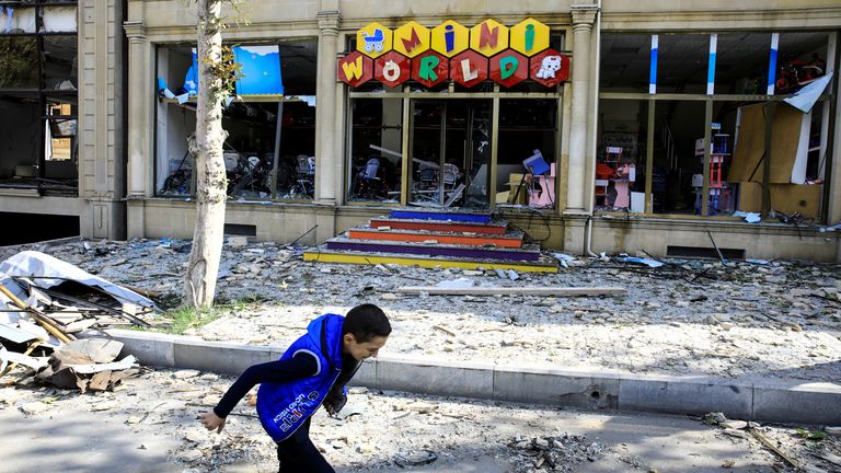 Un garçon passe devant un magasin endommagé après des allégations d'attaque à la roquette sur Ganja