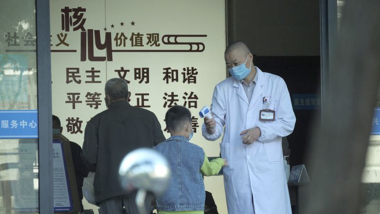 Des gens font vérifier leur température avant d'entrer dans un hôpital de Jiaxing, dans l'est de la Chine