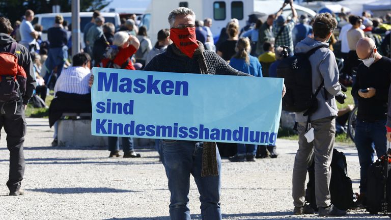 Un homme tenant une pancarte disant `` Les masques sont de la maltraitance des enfants ''