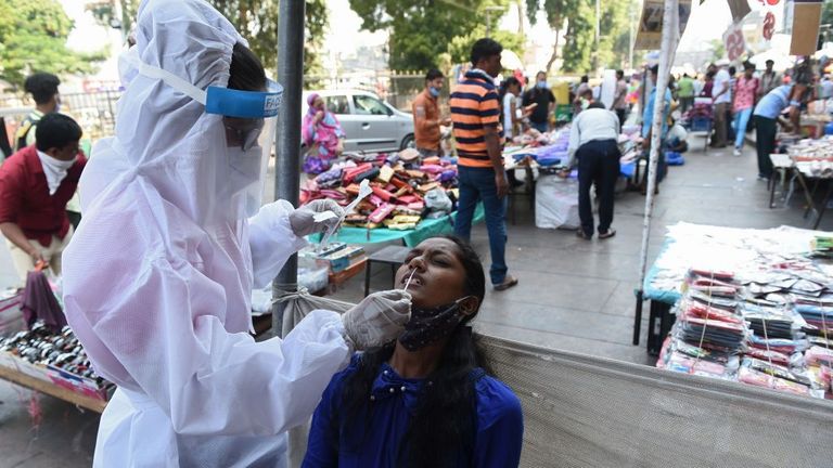 Un agent de santé recueille un échantillon sur écouvillon d'une femme pour tester le coronavirus Covid-19 sur un marché à Ahmedabad le 29 octobre 2020. - L'Inde a dépassé le 29 octobre huit millions de cas de coronavirus, le deuxième pays le plus touché au monde se préparer à une éventuelle deuxième vague avant l'hiver et à une série de fêtes religieuses.  (Photo par SAM PANTHAKY / AFP) (Photo par SAM PANTHAKY / AFP via Getty Images)