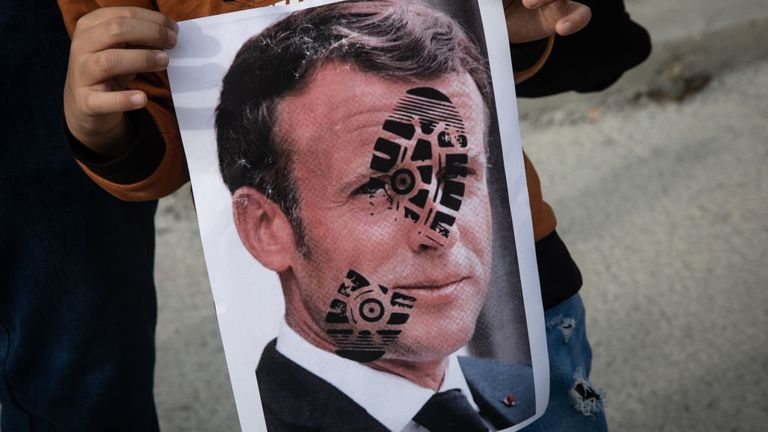 Un garçon d'Istanbul tient une affiche représentant une empreinte sur le visage du président français