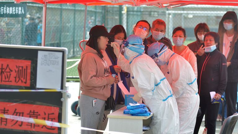 Des travailleurs médicaux en combinaison de protection effectuent des tests sur écouvillon à Qingdao