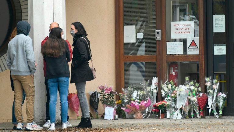 Des fleurs ont été déposées à l'entrée d'un collège de Conflans-Sainte-Honorine, à 30 km au nord-ouest de Paris, le 17 octobre 2020, après qu'un enseignant a été décapité par un agresseur abattu par des policiers.