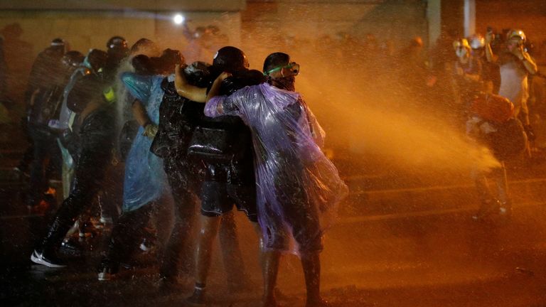 Les manifestants forment une ligne alors qu'ils se protègent des canons à eau lors d'une manifestation anti-gouvernementale alors que les législateurs débattent du changement de constitution, devant le parlement à Bangkok, Thaïlande, le 17 novembre 2020. REUTERS / Jorge Silva