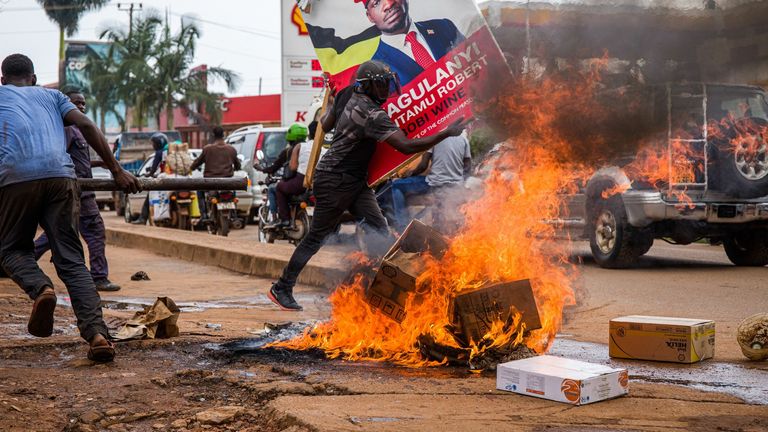 Un partisan de Bobi Wine portant une affiche de campagne pendant les manifestations 