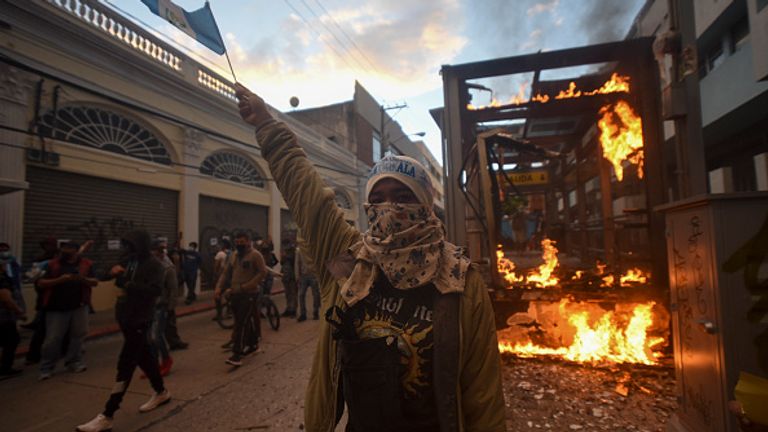Un arrêt de bus brûle alors que les gens manifestaient samedi à Guatemala City