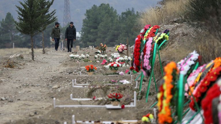 Des hommes marchent le long des tombes de soldats et de civils tués lors d'un conflit militaire dans la région séparatiste du Haut-Karabakh, à Stepanakert