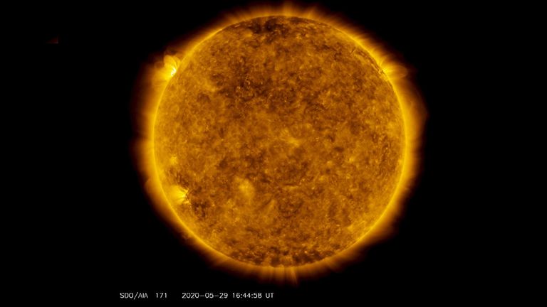 Sur le côté supérieur gauche de cette image du 29 mai 2020, de l'observatoire de la dynamique solaire de la NASA - montré ici dans la longueur d'onde de 171 angströms, qui est généralement colorisée en or - on peut voir une tache de lumière planer au-dessus de l'horizon gauche.  Cette lumière émane d'un matériau solaire traçant des lignes de champ magnétique qui planent au-dessus d'un ensemble de taches solaires sur le point de tourner sur le membre gauche du Soleil.  Crédit: NASA / Observatoire de la dynamique solaire / Joy Ng