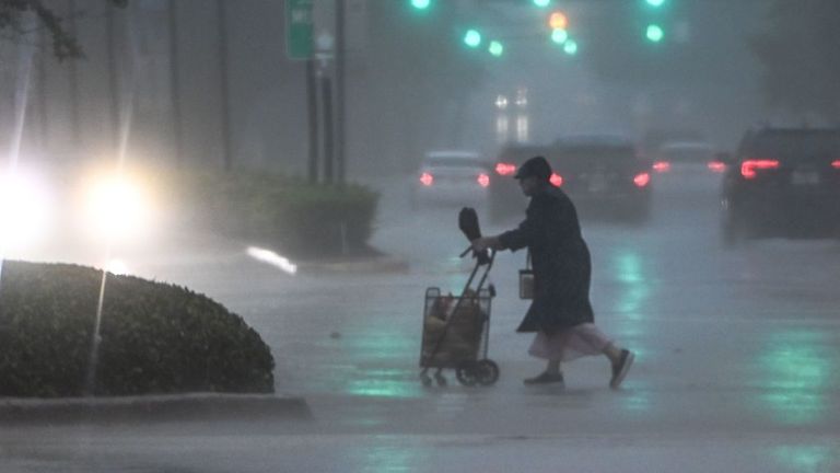 Une femme traverse la rue lors d'une forte pluie et vent à Miami