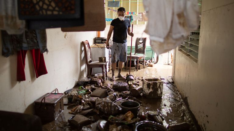 Un homme regarde ses affaires qui ont été couvertes de boue après les inondations causées par le typhon