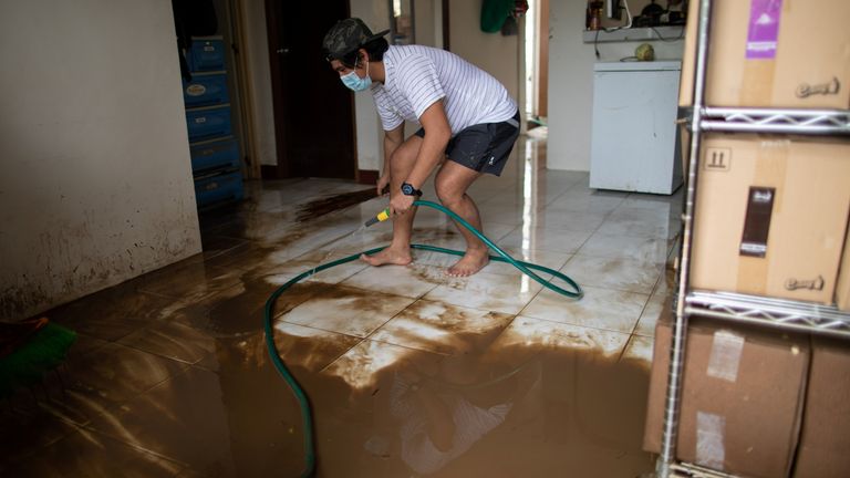 Un homme nettoie une maison couverte de boue suite aux inondations causées par le typhon Goni