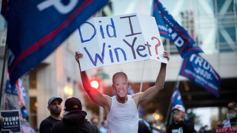 Un partisan de Trump porte un masque du candidat démocrate américain Biden et porte une pancarte lors d'une manifestation à Philadelphie