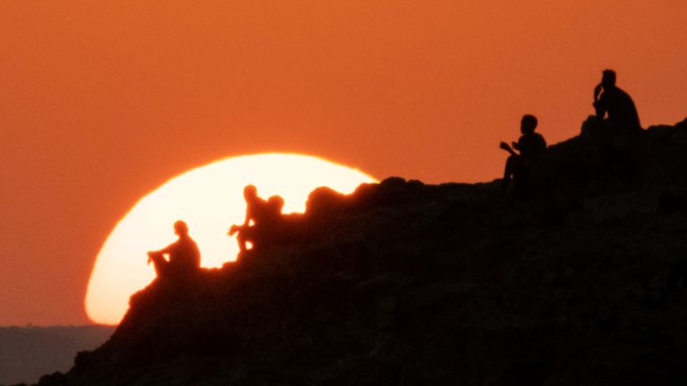 Les réfugiés éthiopiens qui ont fui le conflit éthiopien du Tigray regardent le coucher du soleil sur une colline du camp de réfugiés d'Um Raquba dans l'État soudanais de Gedaref, le 12 décembre 2020 (Photo de Yasuyoshi CHIBA / AFP) (Photo de YASUYOSHI CHIBA / AFP via Getty Images)