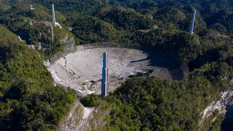 Cette vue aérienne montre les dommages à l'observatoire d'Arecibo après la rupture de l'un des principaux câbles retenant le récepteur à Arecibo, Porto Rico, le 1er décembre 2020. - Le radiotélescope de Porto Rico, qui jouait autrefois dans un film de James Bond, s'est effondré Mardi, lorsque sa plate-forme de réception de 900 tonnes a chuté de 140 mètres et s'est écrasée sur l'antenne radio ci-dessous.  (Photo de Ricardo ARDUENGO / AFP) (Photo de RICARDO ARDUENGO / AFP via Getty Images)