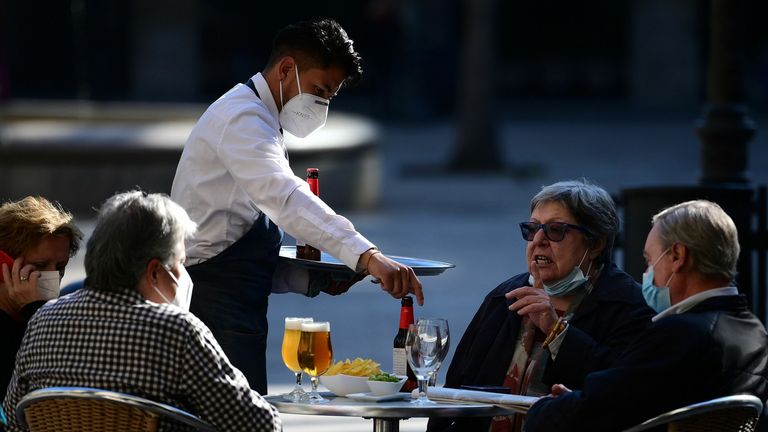 Un serveur sert des clients dans un restaurant de Barcelone le 23 novembre 2020, alors que des bars, des restaurants et des cinémas ont été autorisés à rouvrir dans la région nord-est de l'Espagne de la Catalogne après avoir été fermés pendant plus d'un mois dans le cadre de mesures visant à ralentir les infections à coronavirus.  (Photo par LLUIS GENE / AFP) (Photo par LLUIS GENE / AFP via Getty Images)
