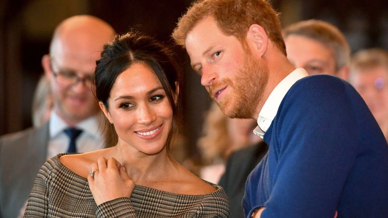 Le prince Harry chuchote à Meghan Markle alors qu'ils regardent un spectacle de danse du Jukebox Collective dans la salle de banquet lors d'une visite au château de Cardiff en 2018