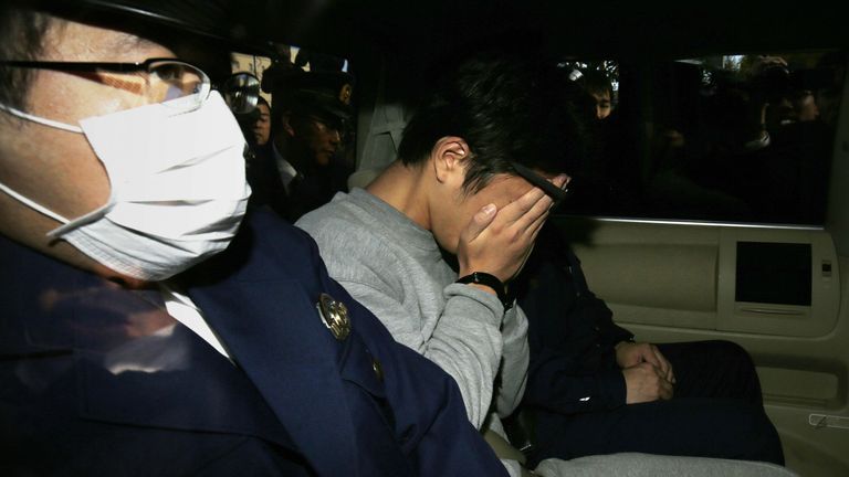 Le suspect Takahiro Shiraishi (C) se couvre le visage avec ses mains alors qu'il est transporté au bureau du procureur depuis un poste de police de Tokyo le 1er novembre 2017. la police a trouvé neuf cadavres démembrés pourrissants dans sa maison, a avoué avoir tué toutes ses victimes sur une virée de deux mois après les avoir contactés via Twitter, rapportent les médias.  / AFP PHOTO / JIJI PRESS / STR / Japan OUT (le crédit photo doit se lire STR / AFP via Getty Images)