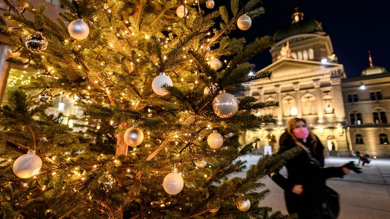 Une femme portant un masque protecteur passe devant un arbre de Noël en face de la Chambre du Parlement suisse à Berne, Suisse