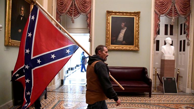Un partisan de Donald Trump porte un drapeau de bataille confédéré dans le Capitole américain