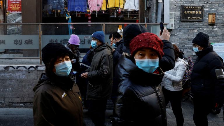 Des personnes portant des masques faciaux à la suite de l'épidémie de coronavirus (COVID-19) passent devant des magasins le long de l'allée Yandaixiejie, à Pékin, en Chine, le 16 janvier 2021. 