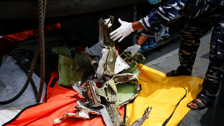 Un membre de la marine indonésienne inspecte un morceau de débris d'avion