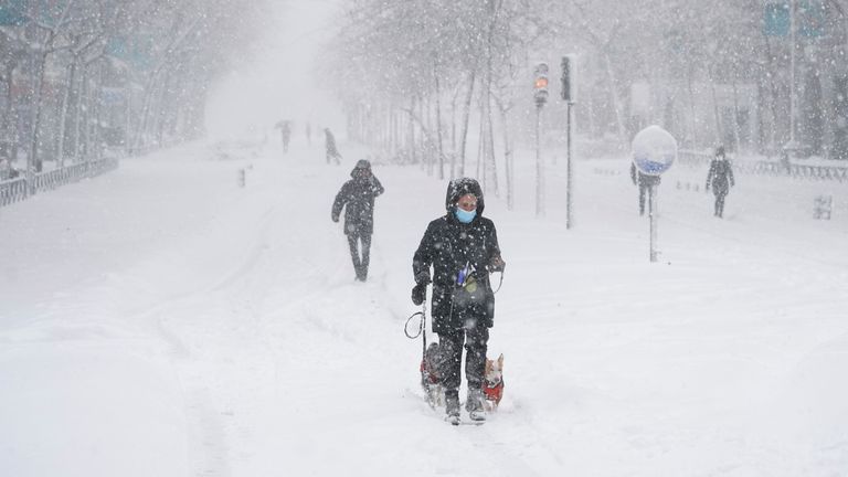 Les gens marchent et skient au centre-ville lors d'une forte chute de neige à Madrid