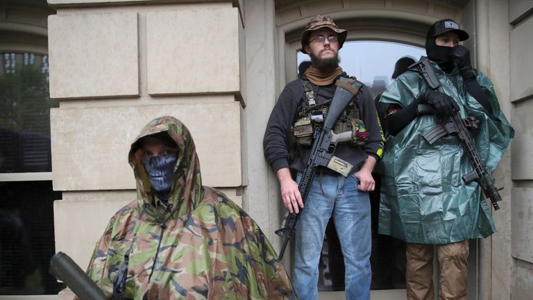 Les manifestants se tiennent avec leurs fusils lors d'un rassemblement au State Capitol à Lansing, Michigan, le jeudi 14 mai 2020 (AP Photo / Paul Sancya)