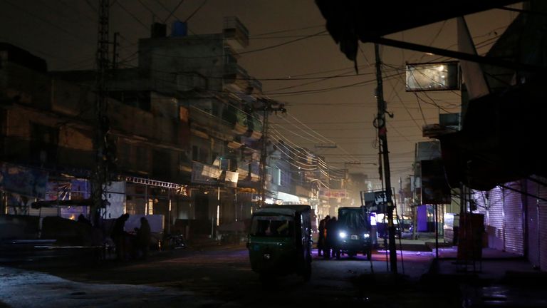 Les gens se découpent sur les phares des véhicules dans une rue sombre lors de pannes de courant généralisées à Rawalpindi, Pakistan