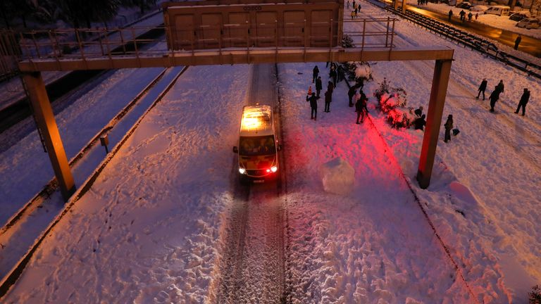 Un véhicule d'urgence passe devant des personnes marchant dans la neige sur l'autoroute M-30, à Madrid, Espagne, le 9 janvier 2021. REUTERS / Susana Vera
