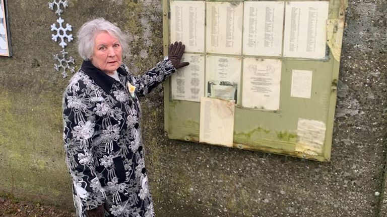 Winnifred Carmel Larkin, photographiée à côté d'une liste des noms d'enfants décédés sur le site des Tuam